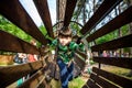 Little boy playing at rope adventure park. Summer holidays concept. Cute child having fun in net tunnel. Modern amusement park for Royalty Free Stock Photo