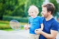 Little boy playing badminton with dad on the playground