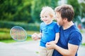 Little boy playing badminton with dad on the playground