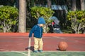 Little boy playing a basketball on the playground on a sunny day.