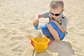 Little boy playing on the beach in the sand. Child sculpts figures out of the sand. Activities in the summer on the sea