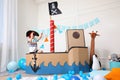 Little boy playing with binoculars in pirate cardboard ship at home. Child`s room interior Royalty Free Stock Photo