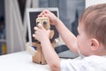 little boy playing with a cardboard robot at home on a white table