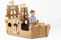 Little boy playing with cardboard ship on white background. Happy kids. Cute child dressed as a sailor. Childhood. Royalty Free Stock Photo