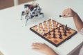 A little boy is playing chess with a gray robot. Robot plays for whites