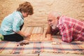 Little boy playing chess with his Grandfather. Chess hobbies - granddad with grandson on a playing chess. Royalty Free Stock Photo