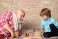 Little boy playing chess with his Grandfather. Chess piece. Senior man thinking about his next move in a game of chess. Royalty Free Stock Photo