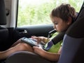 Little boy playing on computer tablet in the car