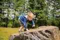 Little boy playing in a field near the big stones Royalty Free Stock Photo
