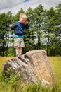 Little boy playing in a field near the big stones Royalty Free Stock Photo