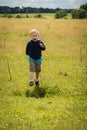 Little boy playing in a field near the big stones Royalty Free Stock Photo