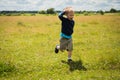 Little boy playing in a field near the big stones Royalty Free Stock Photo