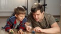 Little boy playing with his father with toy cars on floor. Children playing alone, development and education, games at home Royalty Free Stock Photo