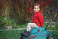 Little boy playing at a lawn mower in autumn Royalty Free Stock Photo