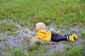 Little boy playing outdoor in a muddy puddle on a rainy fall day Royalty Free Stock Photo