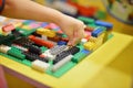 Little boy playing plastic blocks construction indoor