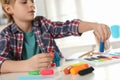 Little boy playing with plasticine at table, closeup. Creative hobby