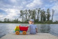 Little boy playing at riverside with dump truck loaded with stones Royalty Free Stock Photo