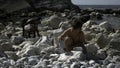 A little boy is playing with rocks on the beach. Creative. A child sitting next to the sea who is playing with pebbles. Royalty Free Stock Photo