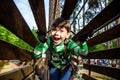 Little boy playing at rope adventure park. Summer holidays concept. Cute child having fun in net tunnel. Modern amusement park for Royalty Free Stock Photo