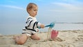 Little boy playing on the sandy beach with toys and using a shovel to dig sand. Happiness and excitement of a family vacation and Royalty Free Stock Photo