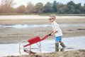 A little boy is playing on the sandy river bank in summer at sunset.