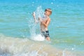 A little boy playing in the sea water. A child jumps from the sea. A tropical vacation with children. Royalty Free Stock Photo