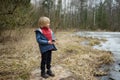 Little boy playing on shore of forest lake on early spring day. Outdoor activity for kids Royalty Free Stock Photo