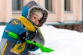 Little boy playing with snow and spade