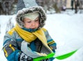 Little boy playing with snow and spade