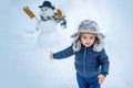 Little boy playing with snowman in winter park. Winter portrait of cute child in snow Garden. People in snow. Happy Royalty Free Stock Photo
