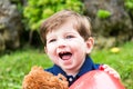 little boy playing with a teddy bear and a red balloon in the garden Royalty Free Stock Photo