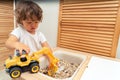 Little boy playing with a toy excavator indoors