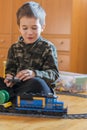 Little boy playing with a toy railway. Little boy playing with railway lying on the floor. Joyful emotions. vertical photo Royalty Free Stock Photo
