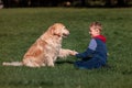 Little boy playing and training golden retriever dog in the field in summer day together. Cute child with doggy pet portrait at Royalty Free Stock Photo