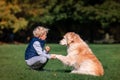 Little boy playing and training golden retriever dog in the field in summer day together. Cute child with doggy pet portrait at Royalty Free Stock Photo