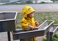 Little boy playing with water pipes in an interactive playground under the rain