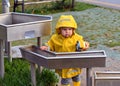 Little boy playing with water pipes in an interactive playground under the rain