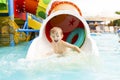 Little boy playing on water slide in outdoor pool on a hot summer day