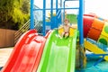 Little boy playing on water slide in outdoor pool on a hot summer day