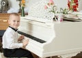 Little boy playing on a white Grand piano. Royalty Free Stock Photo