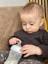 A little boy plays with a baby bottle with a nipple filled with milk formula for feeding Royalty Free Stock Photo