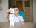 Little boy plays with cubes and puts it together in word Royalty Free Stock Photo