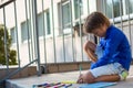 The boy plays with felt-tip pens and books on the school porch Royalty Free Stock Photo