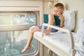 Little boy plays games on tablet sitting on shelf in train Royalty Free Stock Photo