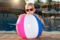 A little boy plays with an inflatable ball in the pool.Water toy and sunglasses for kids. Royalty Free Stock Photo