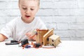 Little boy plays with the robot. Child collects a robot sitting at the table