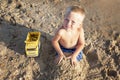 A little boy plays with sand and toys on the beach near the sea Royalty Free Stock Photo