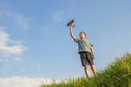 Little boy plays with toy wooden plane. Happy kid playing with toy wooden airplane against sky background Royalty Free Stock Photo