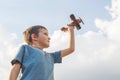 Little boy plays with toy wooden plane. Happy kid playing with toy wooden airplane against sky background Royalty Free Stock Photo